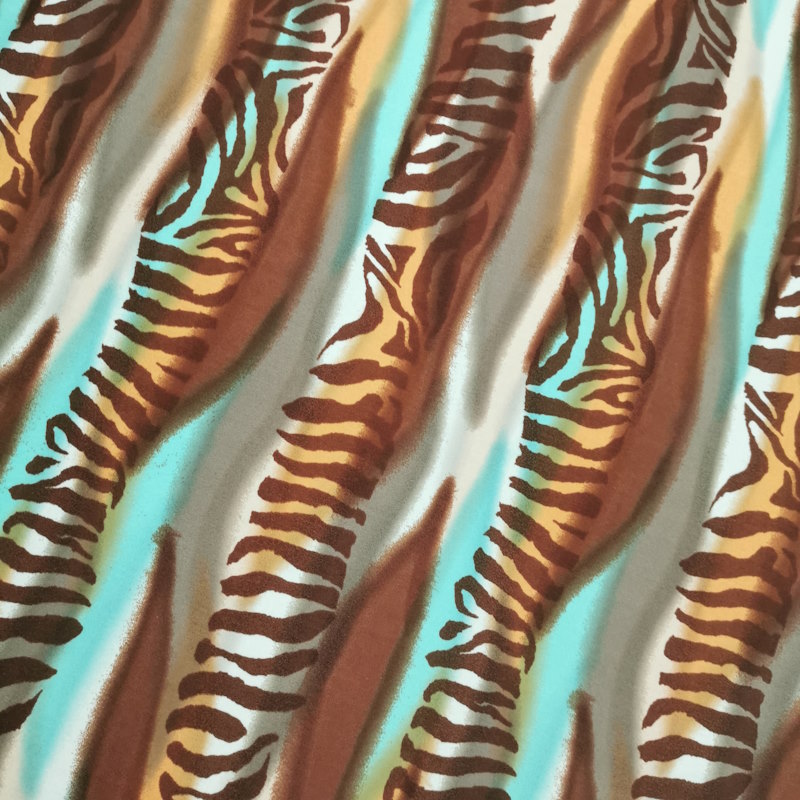 Il s'agit d'un lycra imprimé zèbres à rayures, dans des coloris turquoises, orangés et marron.