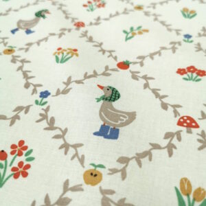 Tissu avec des motifs en quadrillage formant des losanges, avec au centre des petites oies mignonnes et des fleurs colorées.